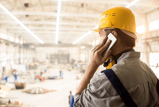 whistleblowing system for the food industry – man in hard hat on phone in warehouse