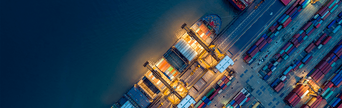 Birds eye view of a shipping container in port lit up at night
