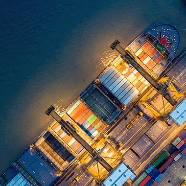 Birdseye view of commercial ship holding industrial containers lit up a in a port at night