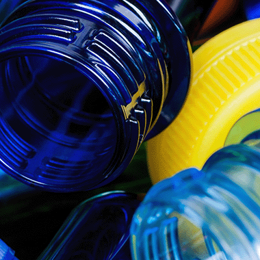Close up view of the top of a plastic blue tubes in a pile with a plastic yellow crew top lid